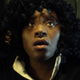 A woman wearing a bus driver uniform looks upward with fear in her face.